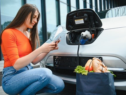 Woman with groceries charging EV 