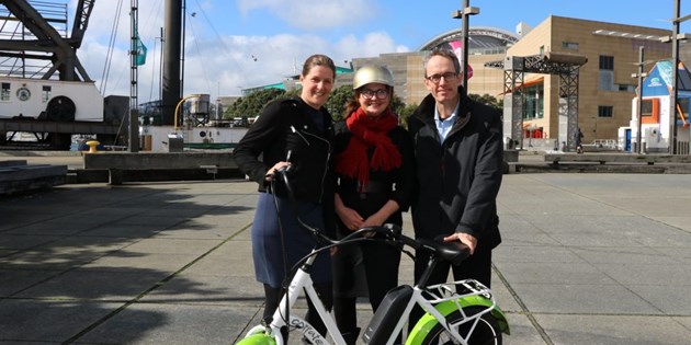 Three people standing with E-bike