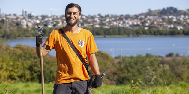 Man with gardening tools and houses in the background