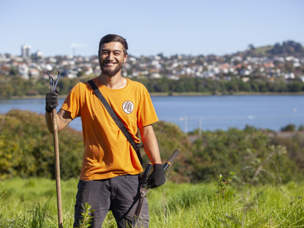 Man with gardening tools and houses in the background