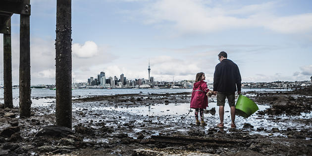 Man and child standing on foreshore of harbour