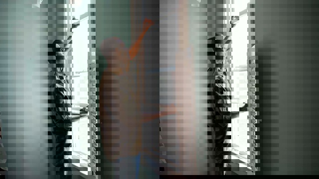 Man installs insect screen on window