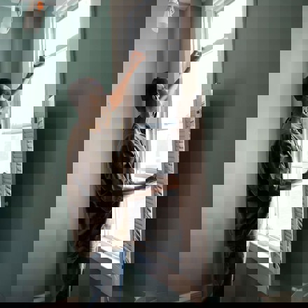 Man installs insect screen on window