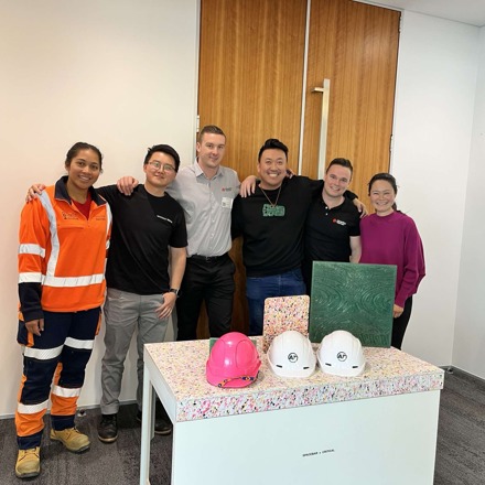 2 women and 4 men stand with their arms around in each other behind product made with reused material