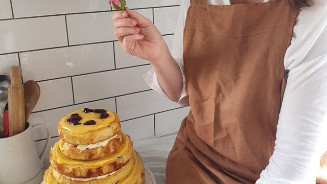 Lady holding fresh flower over beautifully decorated cake