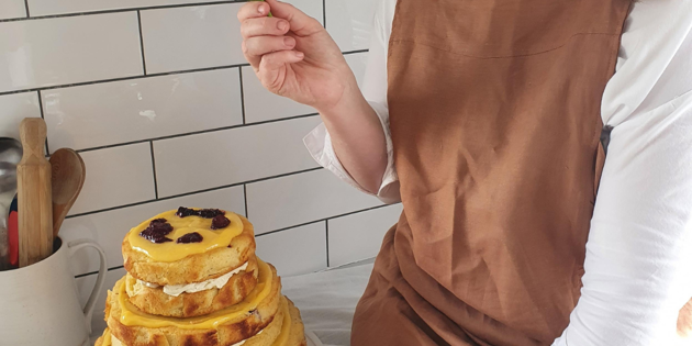Lady holding fresh flower over beautifully decorated cake