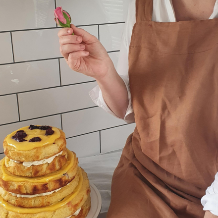 Lady holding fresh flower over beautifully decorated cake