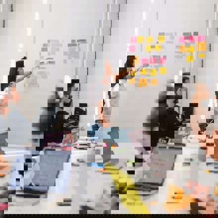 Woman uses sticky notes on wall at meeting