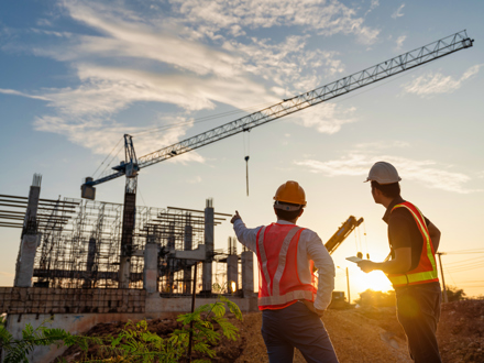 Two men in foreground of construction project and crane