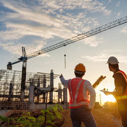 Two men in foreground of construction project and crane