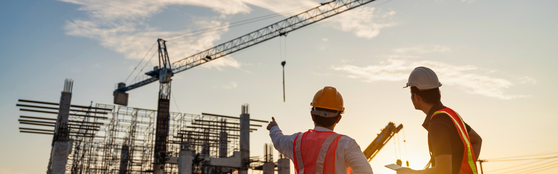 Two men in foreground of construction project and crane