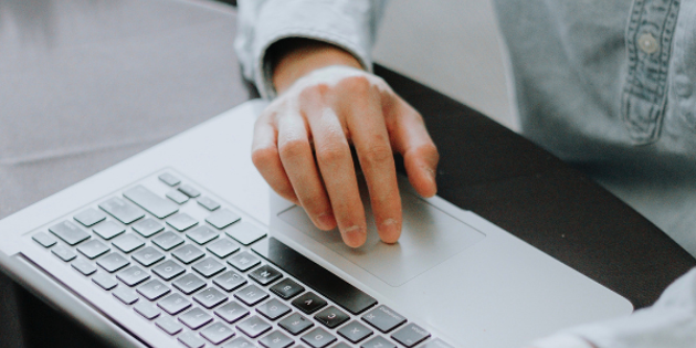 laptop keyboard with hand on mousepad
