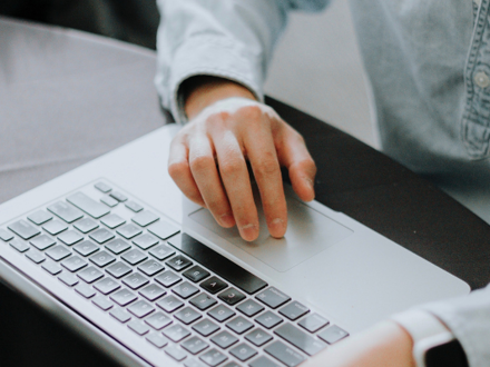laptop keyboard with hand on mousepad