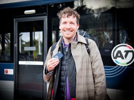 Commuter with AT HOP card in front of bus